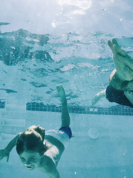 Opa und Enkel tauchen im Schwimmbad bis auf den Grund des Beckens.