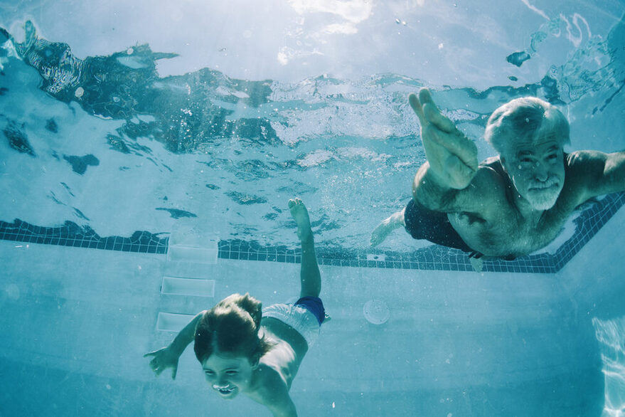 Opa und Enkel tauchen im Schwimmbad bis auf den Grund des Beckens.