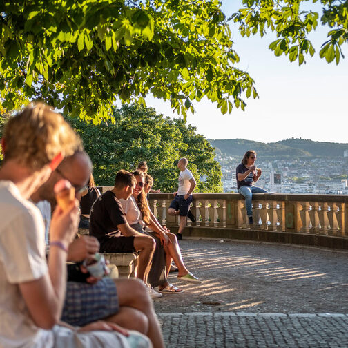 Menschen sitzen am Eugensplatz mit Blick von oben auf die Innenstadt.