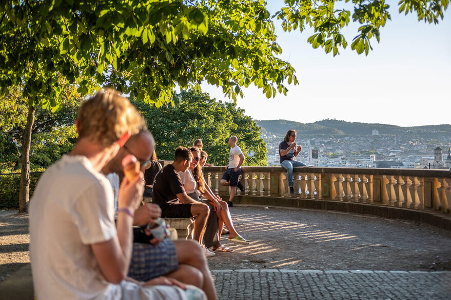 Menschen sitzen am Eugensplatz mit Blick von oben auf die Innenstadt.