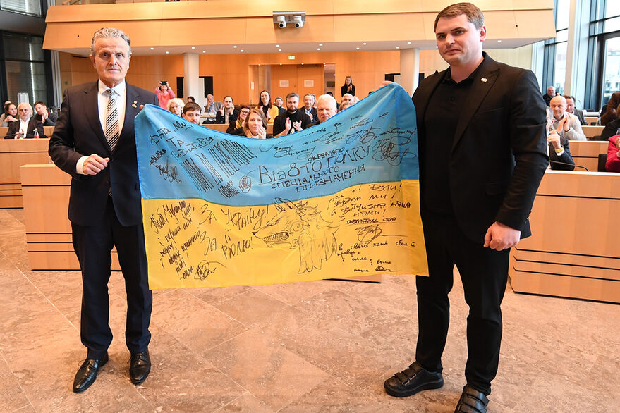 Oberbürgermeister Dr. Frank Nopper (links) und Bürgermeister Mykola Wawryschtschuk aus Chmelnyzkyj halten im Gemeinderat eine signierte ukrainische Flagge.