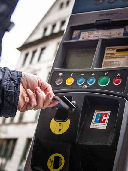 A man pays with a debit card at a parking ticket machine.