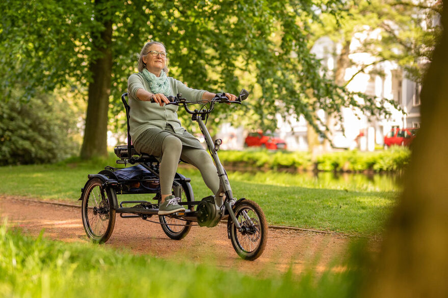 Frau fährt mit einem elektrisch betriebenen dreirädrigen Fahrrad