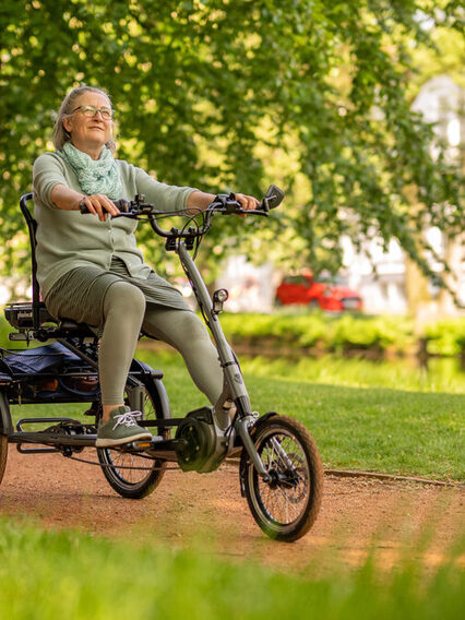 Frau fährt mit einem elektrisch betriebenen dreirädrigen Fahrrad