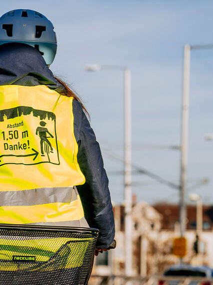 Radfahrerin in Warnweste fährt an einer Zählstation vorbei.