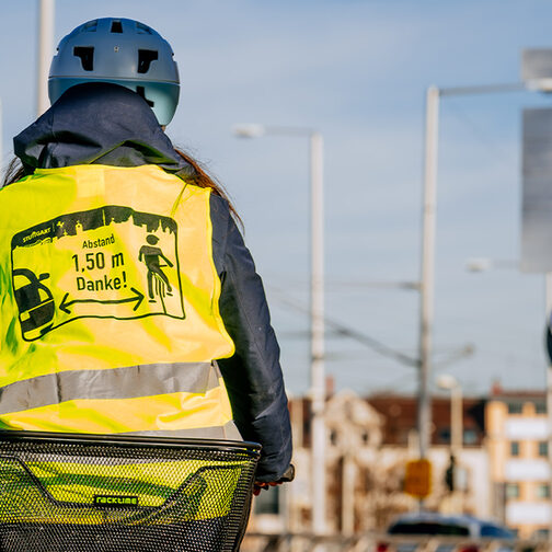Radfahrerin in Warnweste fährt an einer Zählstation vorbei.