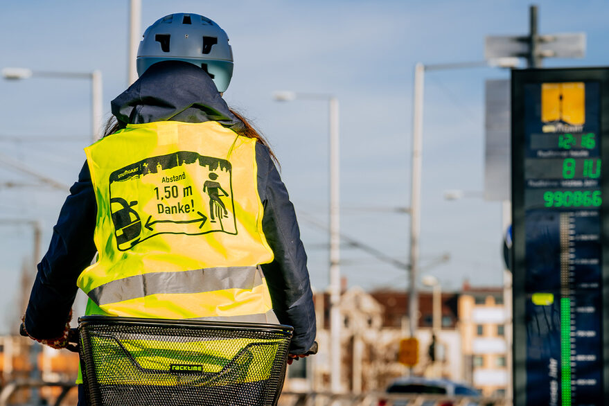 Radfahrerin in Warnweste fährt an einer Zählstation vorbei.