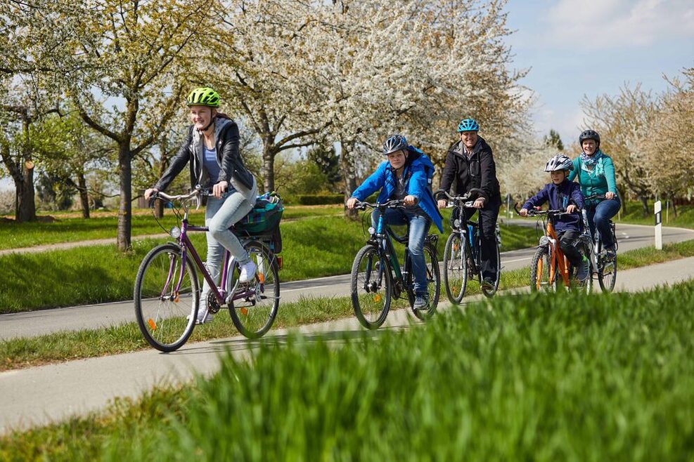 Fünf Menschen fahren mit dem Fahrrad neben einer Bundesstraße.