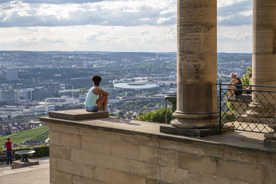 Einige Ausflügler sitzen an der Grabkapelle und genießen den Ausblick auf die Stadt.