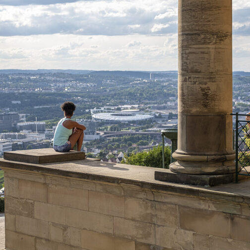 Einige Ausflügler sitzen an der Grabkapelle und genießen den Ausblick auf die Stadt.