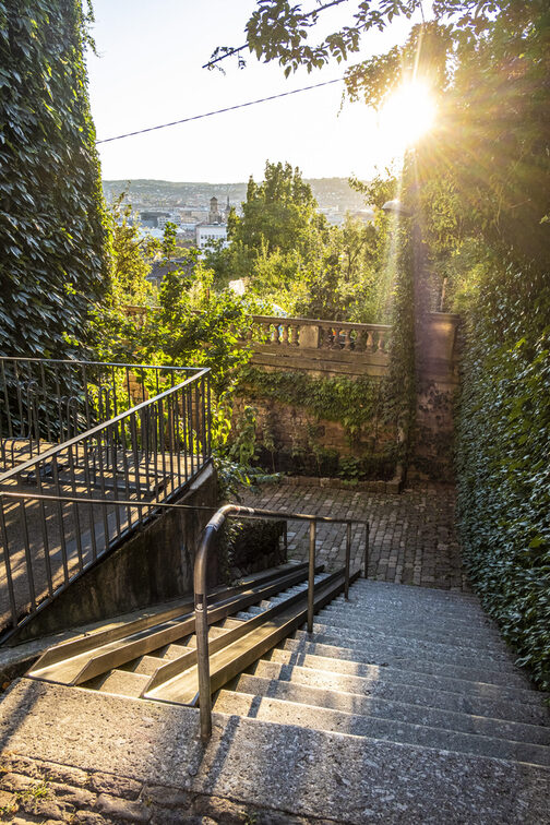 Blick hinunter auf eine Treppe, im Hintergrund ist eine Stadt zu erkennen.