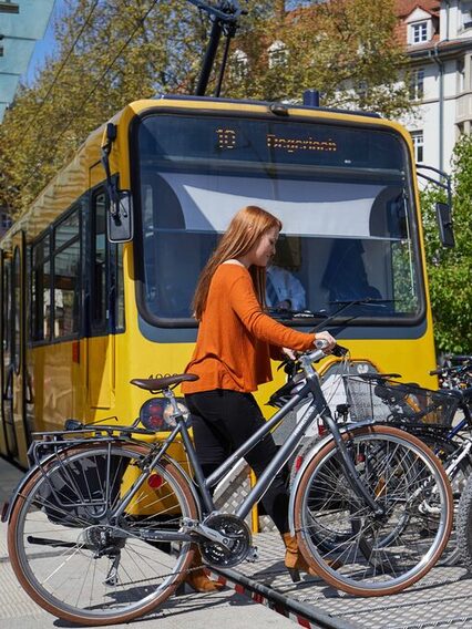 Junge Frau stellt ihr Fahrrad auf den Fahrradwagen der Zahnradbahn.