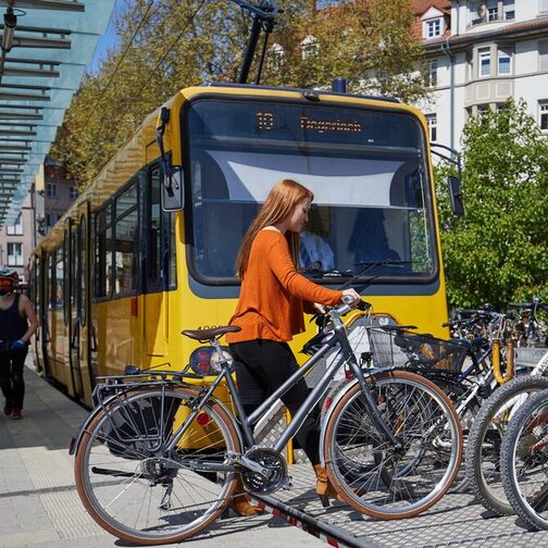 Junge Frau stellt ihr Fahrrad auf den Fahrradwagen der Zahnradbahn.