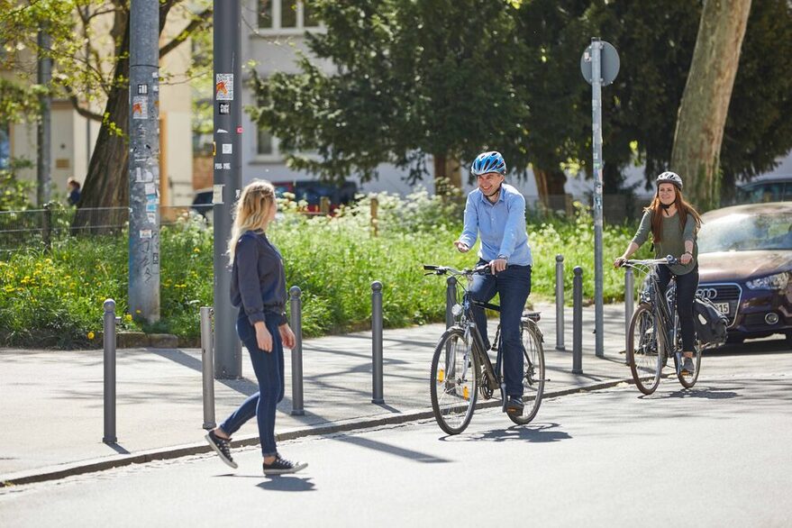 Eine Fußgängerin überquert die Straße vor zwei Radfahrenden.