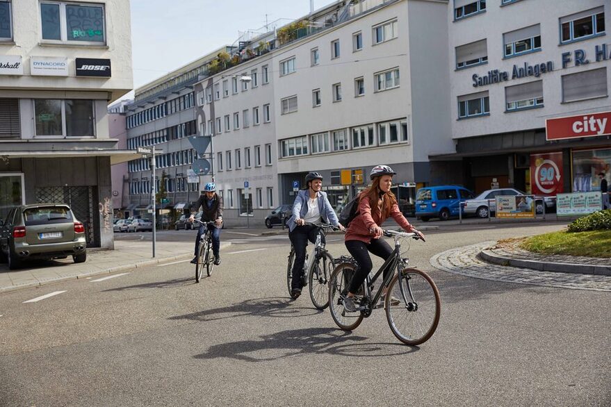 Drei Fahrradfahrer radeln durch einen Kreisverkehr.