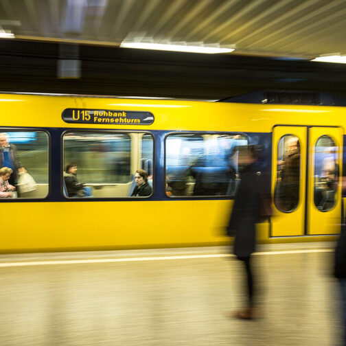 Eine gelbe Stadtbahn fährt an einer Haltstelle ein.