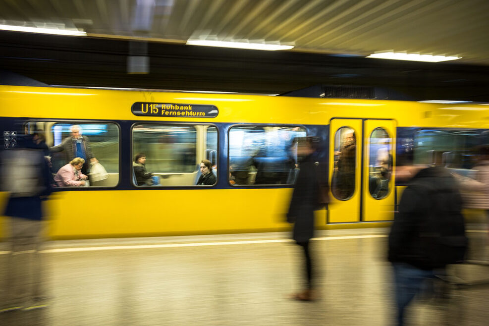 Eine gelbe Stadtbahn fährt an einer Haltstelle ein.