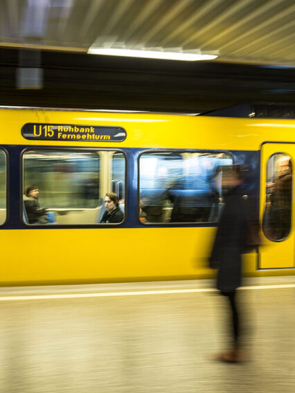 Eine gelbe Stadtbahn fährt an einer Haltstelle ein.