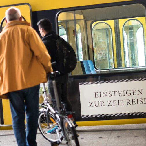 Ein Mann steigt mit seinem Fahrrad in eine Stadtbahn.