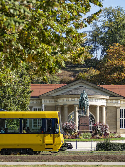 Eine gelbe Stadtbahn fährt vor dem Kursaal in Bad Cannstatt vorbei.
