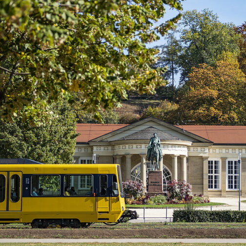 Eine gelbe Stadtbahn fährt vor dem Kursaal in Bad Cannstatt vorbei.