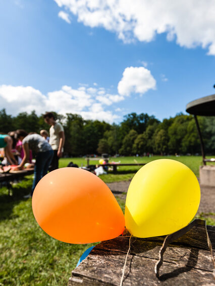 Zu sehen ist ein Grillplatz am Bärensee mit zwei bunten Luftballons im Vordergrund und der Grillstelle im Hintergrund.