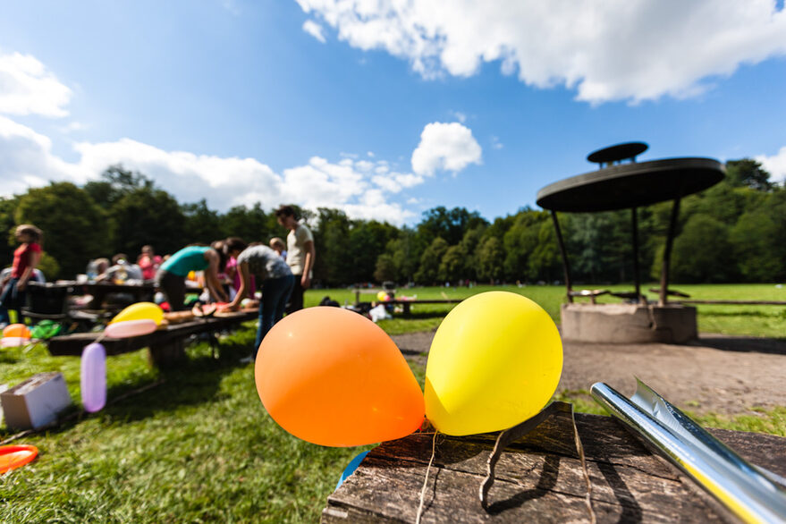 Zu sehen ist ein Grillplatz am Bärensee mit zwei bunten Luftballons im Vordergrund und der Grillstelle im Hintergrund.