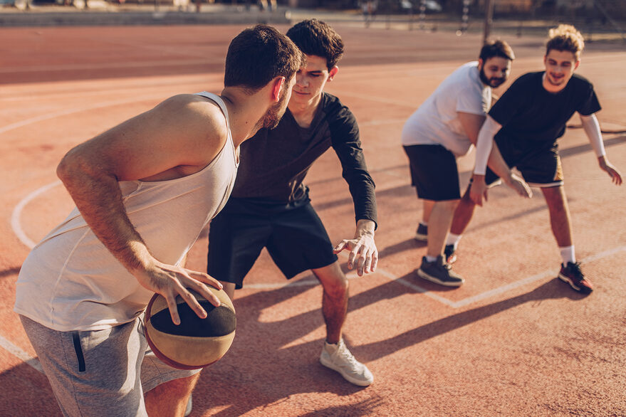 Vier Junge Männer spielen Basketball