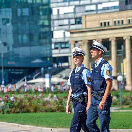 Zwei Polizisten laufen Streife über einen großen Platz in einer Stadt.