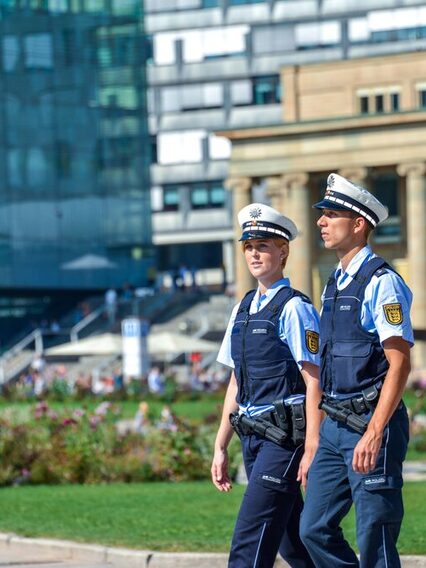 Zwei Polizisten laufen Streife über einen großen Platz in einer Stadt.