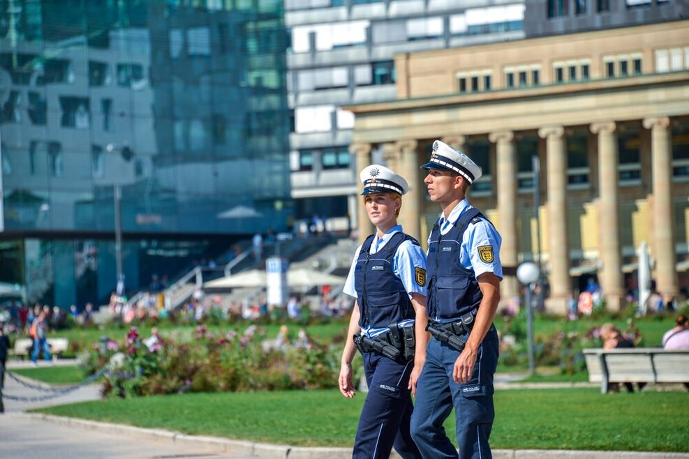 Zwei Polizisten laufen Streife über einen großen Platz in einer Stadt.