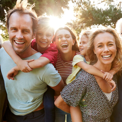 Gruppenbild einer Mehrgenerationenfamilie, die fröhlich in die Kamera lacht