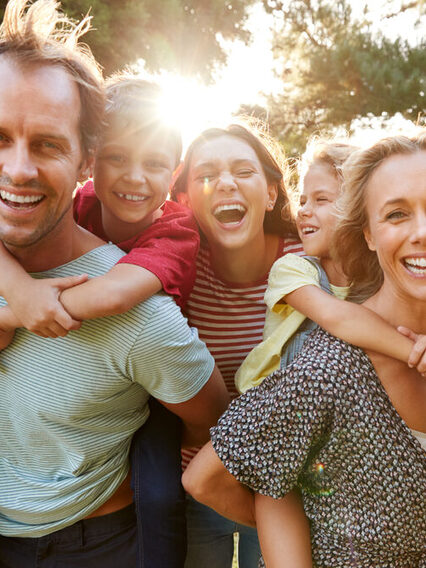 Gruppenbild einer Mehrgenerationenfamilie, die fröhlich in die Kamera lacht