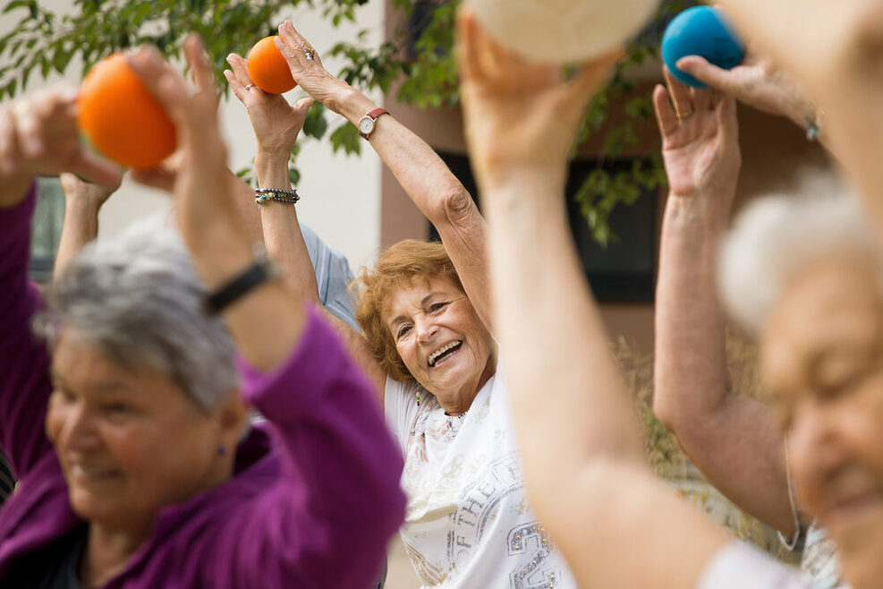 Eine Gruppe älterer Frauen macht Sportübungen mit einem Ball.