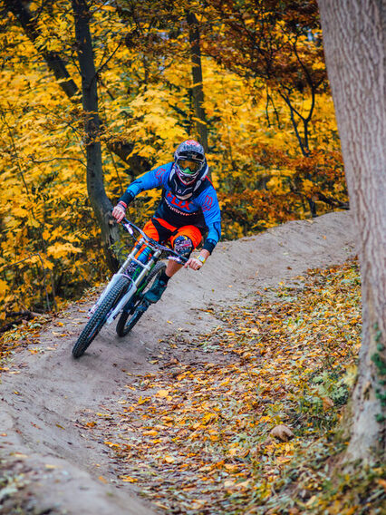 Radfahrer fährt auf einer Downhill-Strecke durch den Wald.