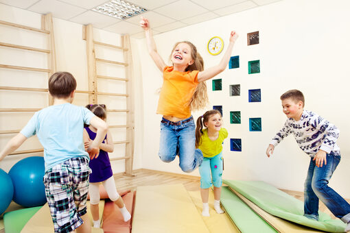 Kinder toben in einem Gymnastikraum.