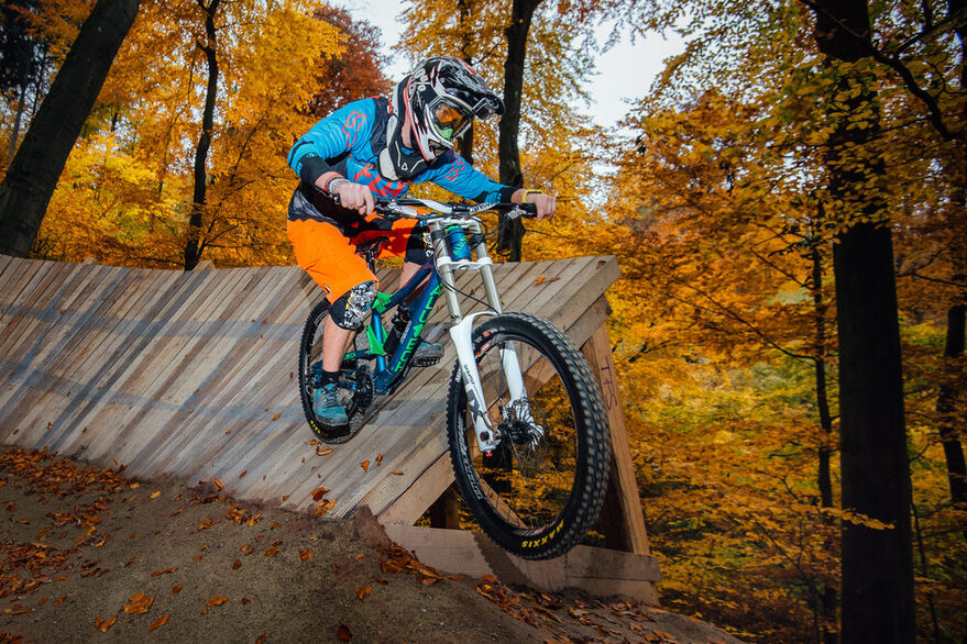 Downhillfahrer fährt eine Rampe entlang.