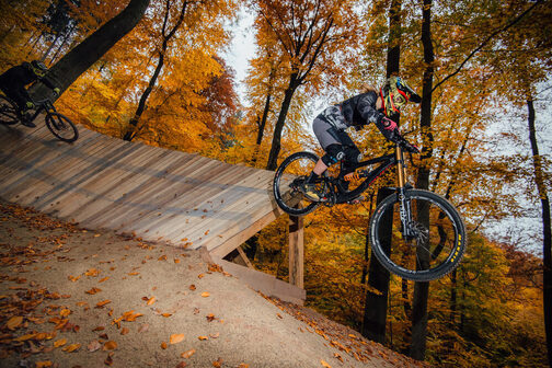 Eine Frau fährt auf einem Fahrrad eine Downhill-Strecke bergab.