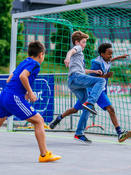 Drei Jungen spielen Fußball.