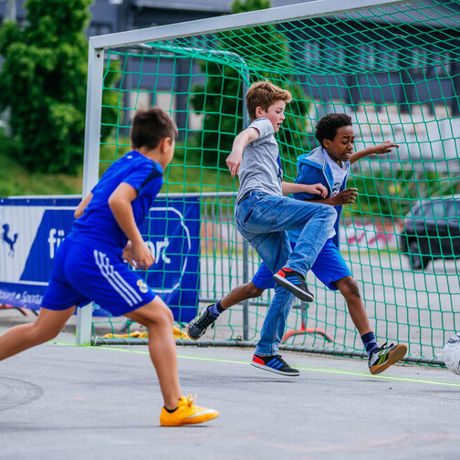 Drei Jungen spielen Fußball.