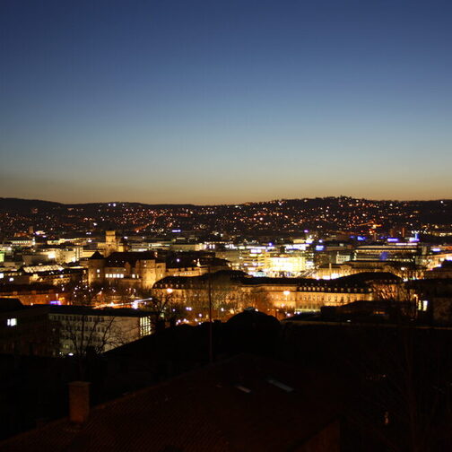 Blick auf eine beleuchtete Stadt kurz nach Sonnenuntergang.