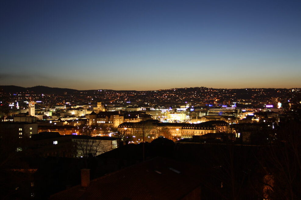 Blick auf eine beleuchtete Stadt kurz nach Sonnenuntergang.