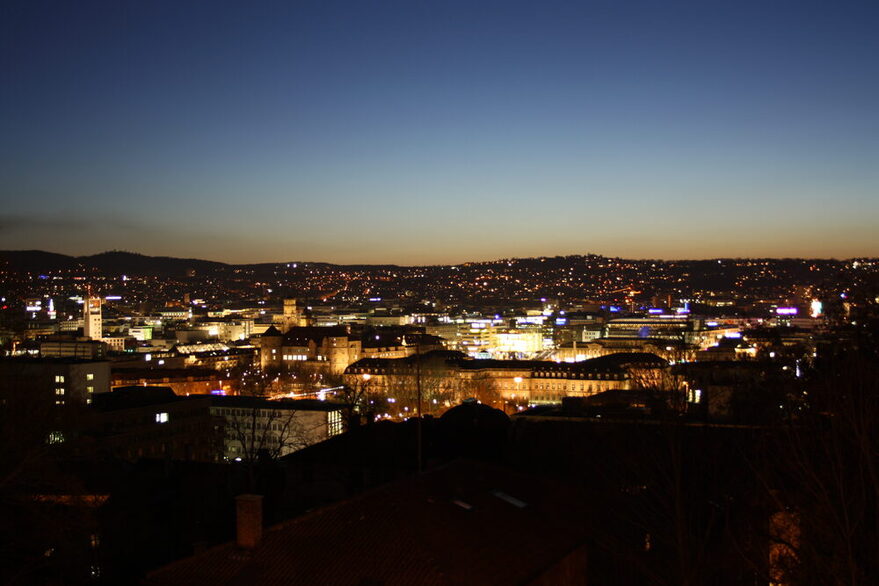 Blick auf eine beleuchtete Stadt kurz nach Sonnenuntergang.