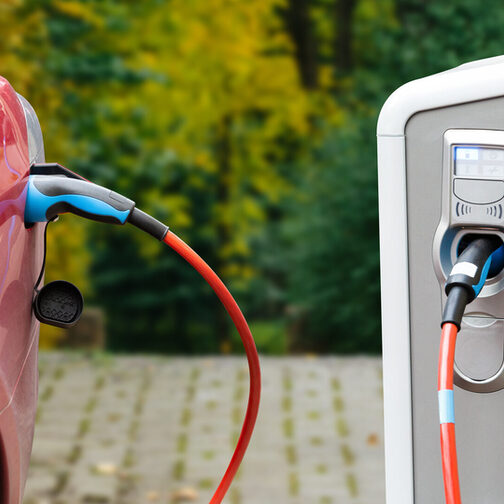 Nahaufname eines ladenden Elektrofahzeugs in rot an einer Ladesäule