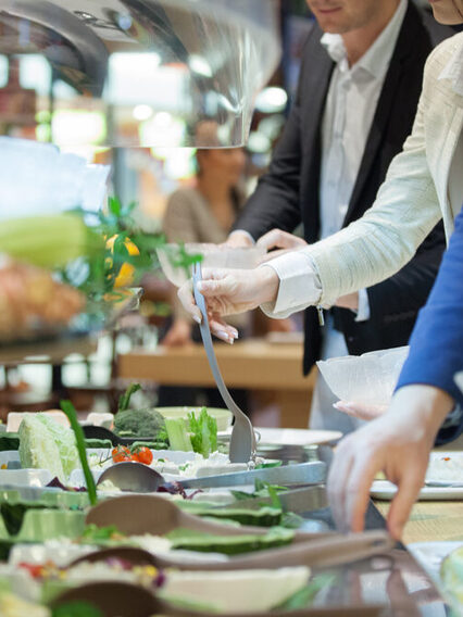 In einer Kantine: Menschen bedienen sich an einem Salat-Buffet.