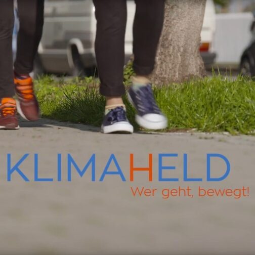 Drei Kinder gehen auf einem Gehweg, auf dem Weg steht der Schriftzug "Ich bin ein Klimaheld".