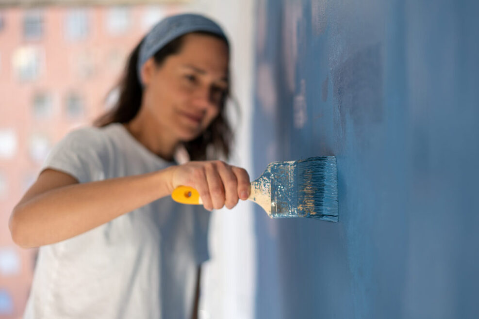 Eine Frau steicht eine Wand blau.