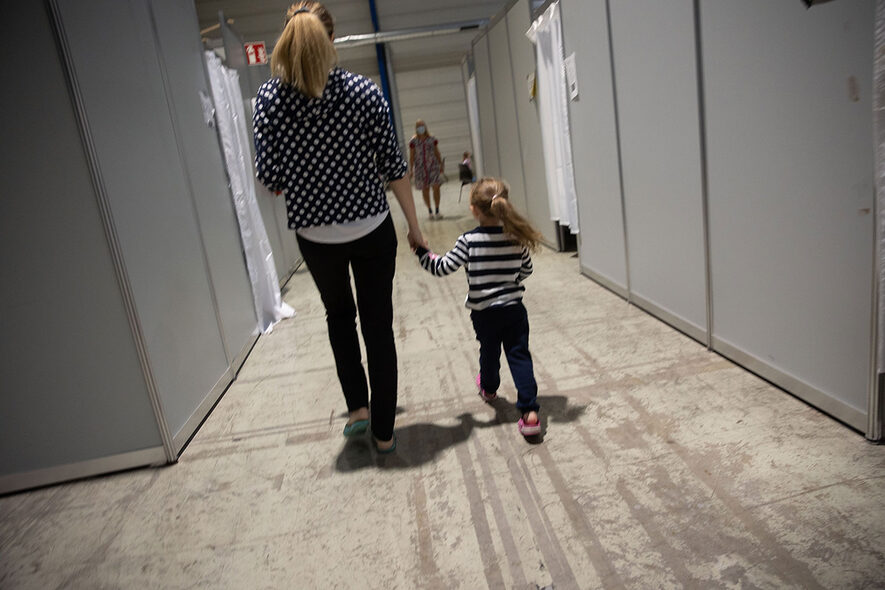 Flüchtlinge aus der Ukraine - Mutter mit Kind an der Hand - Rückansicht - in der Hanns-Martin-Schleyer-Hall