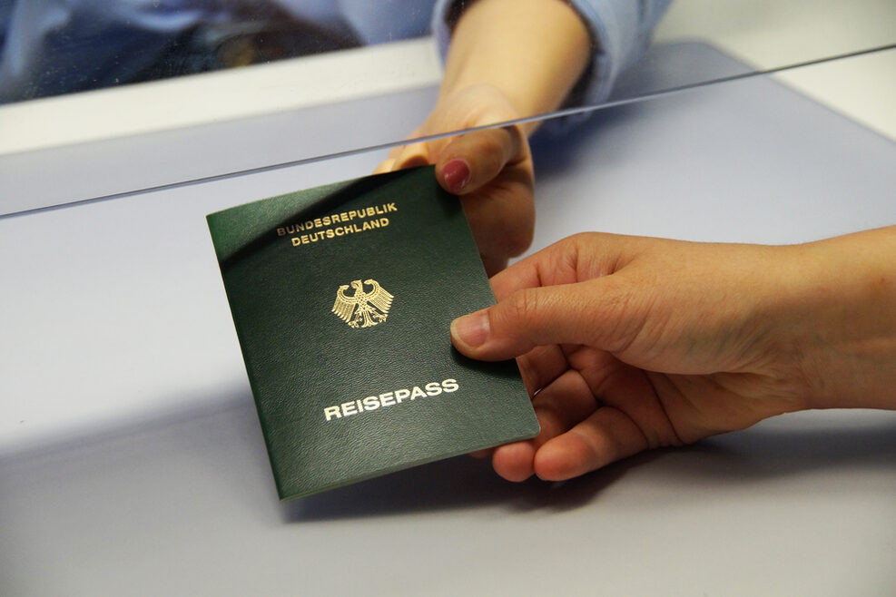 Ein Hand hält einen grünen Reisepass in der Hand.