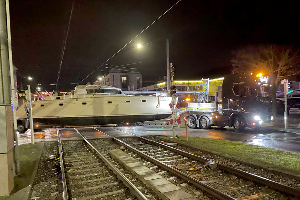 Ein Laster transportiert auf einem Anhänger nachts einen Yacht durch die Stuttgarter Innenstadt.